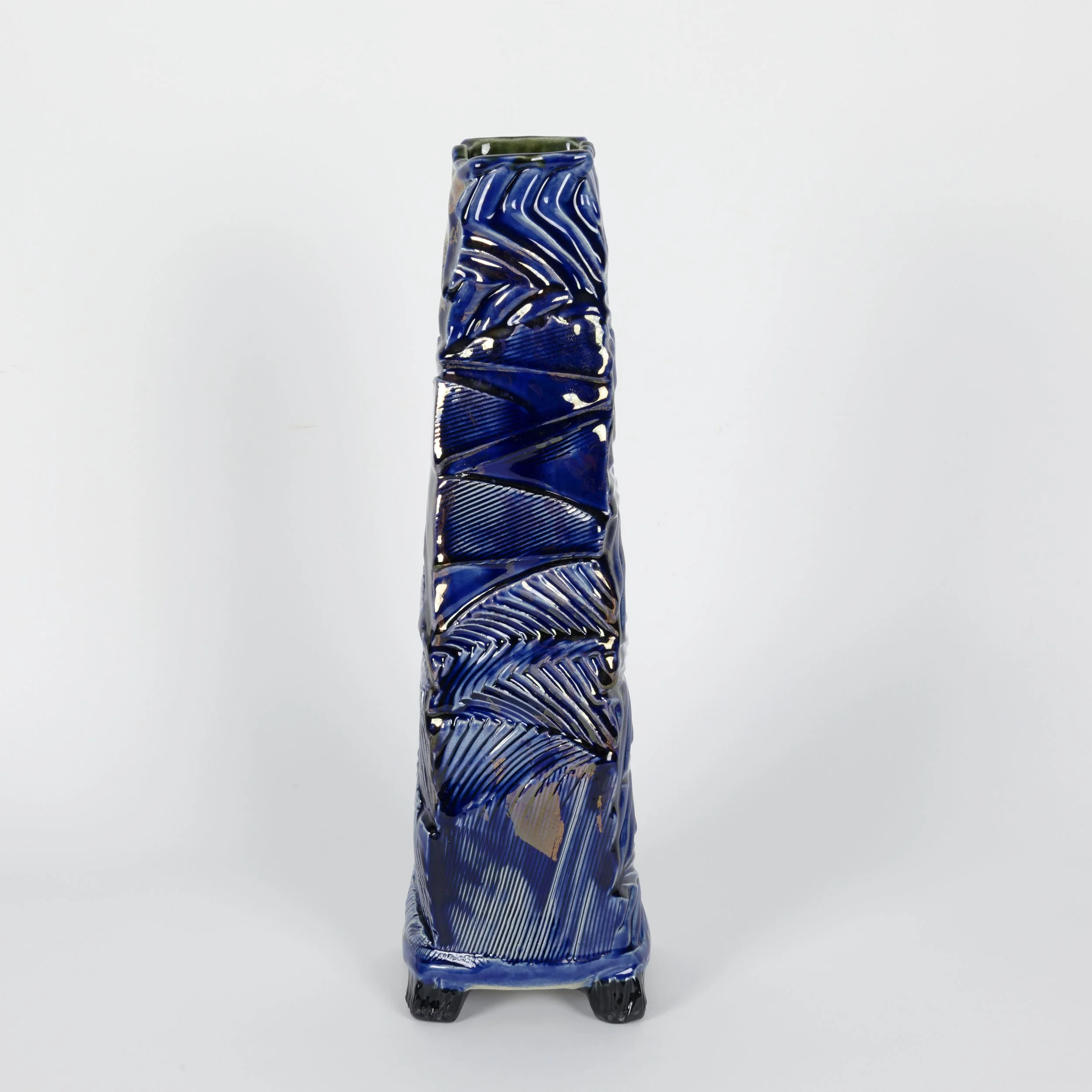 Tall hand-built ceramic vessel with four feet, a square tapered form, rhythmic surface texture, deep blue glazes with layered gold lustre, and a black interior and textured black feet.