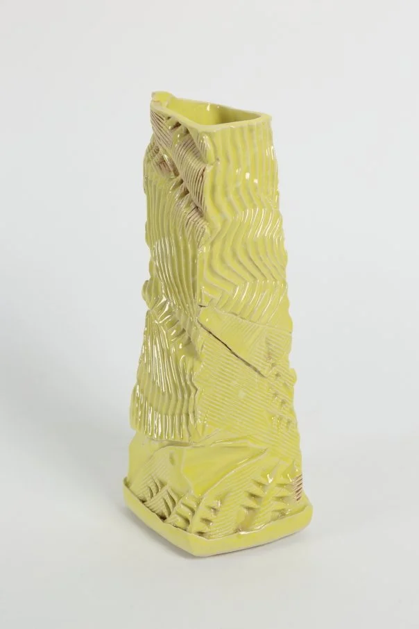 Hand-built ceramic vessel with an asymmetric tapered form and rhythmic surface texture, finished with soft yellow and white glazes and an oxide feature.