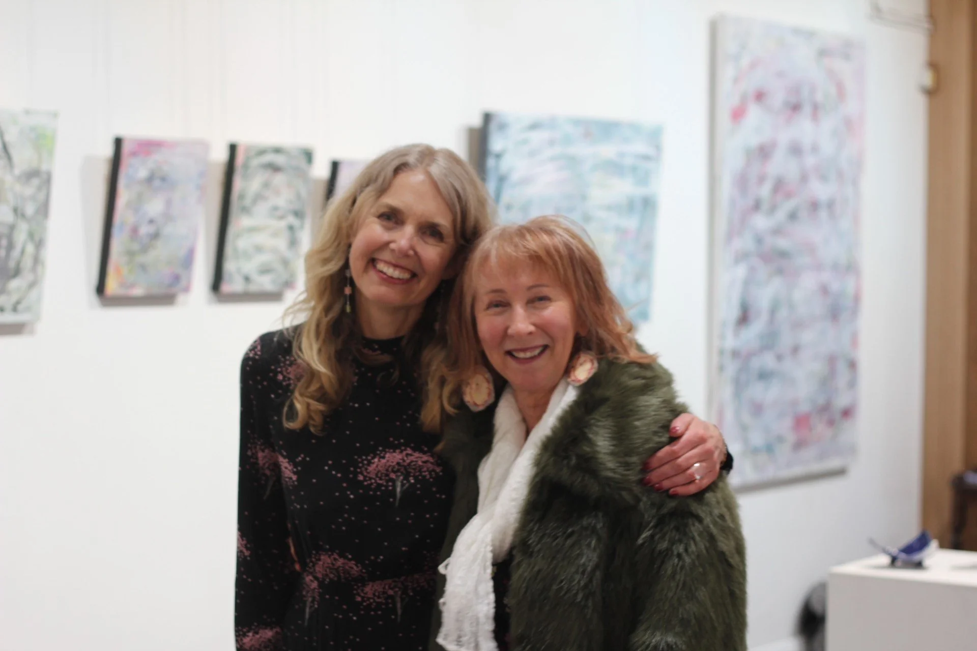 Tonya Blizzard and Jan Alexander, at Harlow Gallery, with abstract paintings in the background.