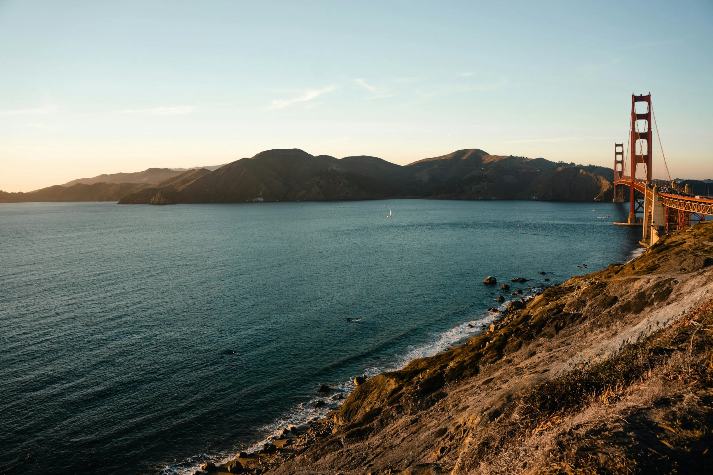 Golden Gate Bridge and the Marin hills across the water in soft evening light.