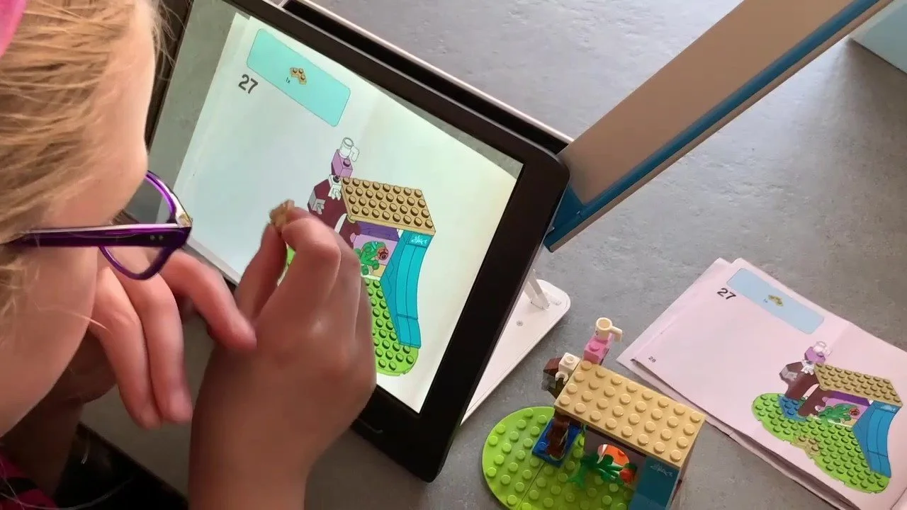 A young girl looking at a video magnifier that is magnifying her lego