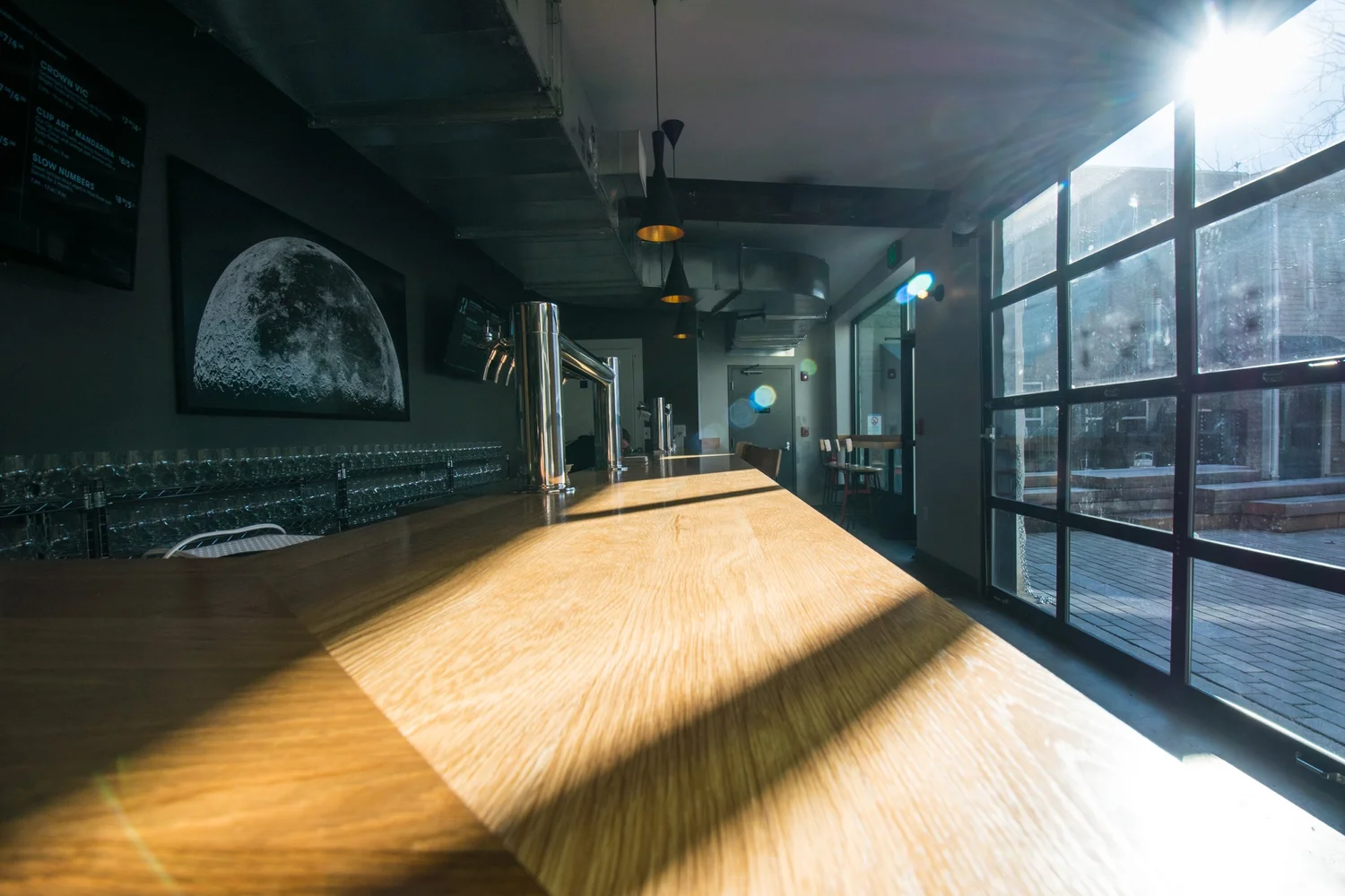 The bar, beer taps, and moon artwork inside Remnant Brewing at Bow Market