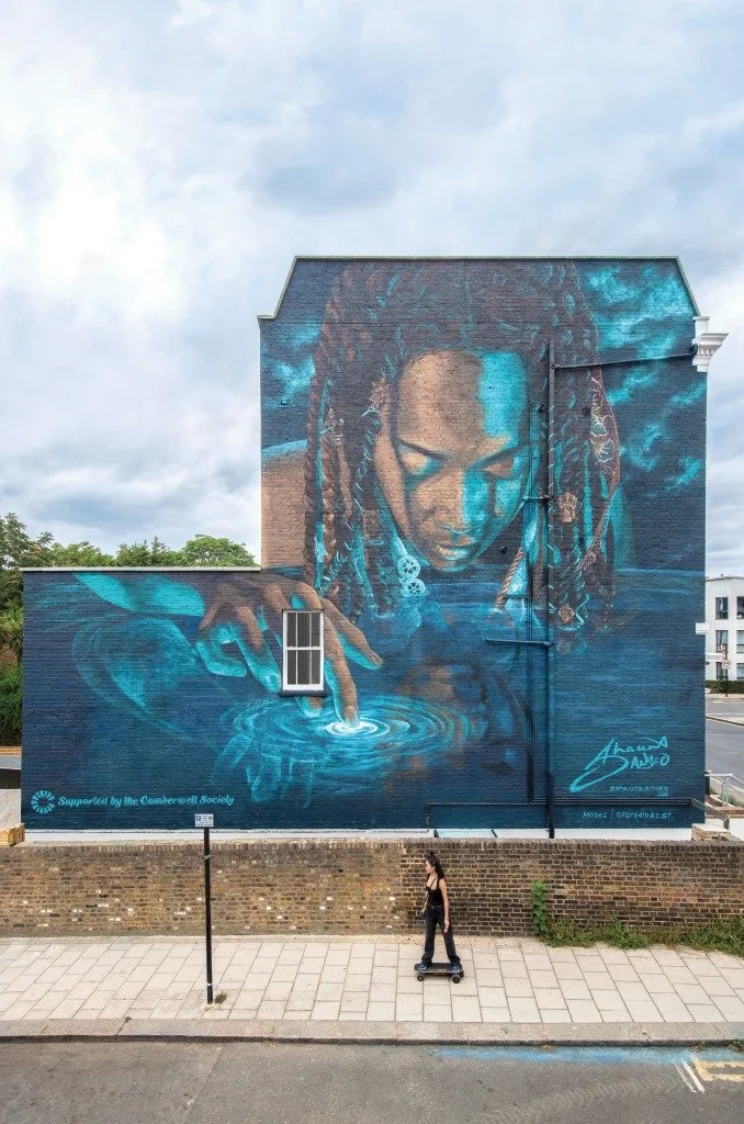 A woman skateboards by a Mural in Camberwell