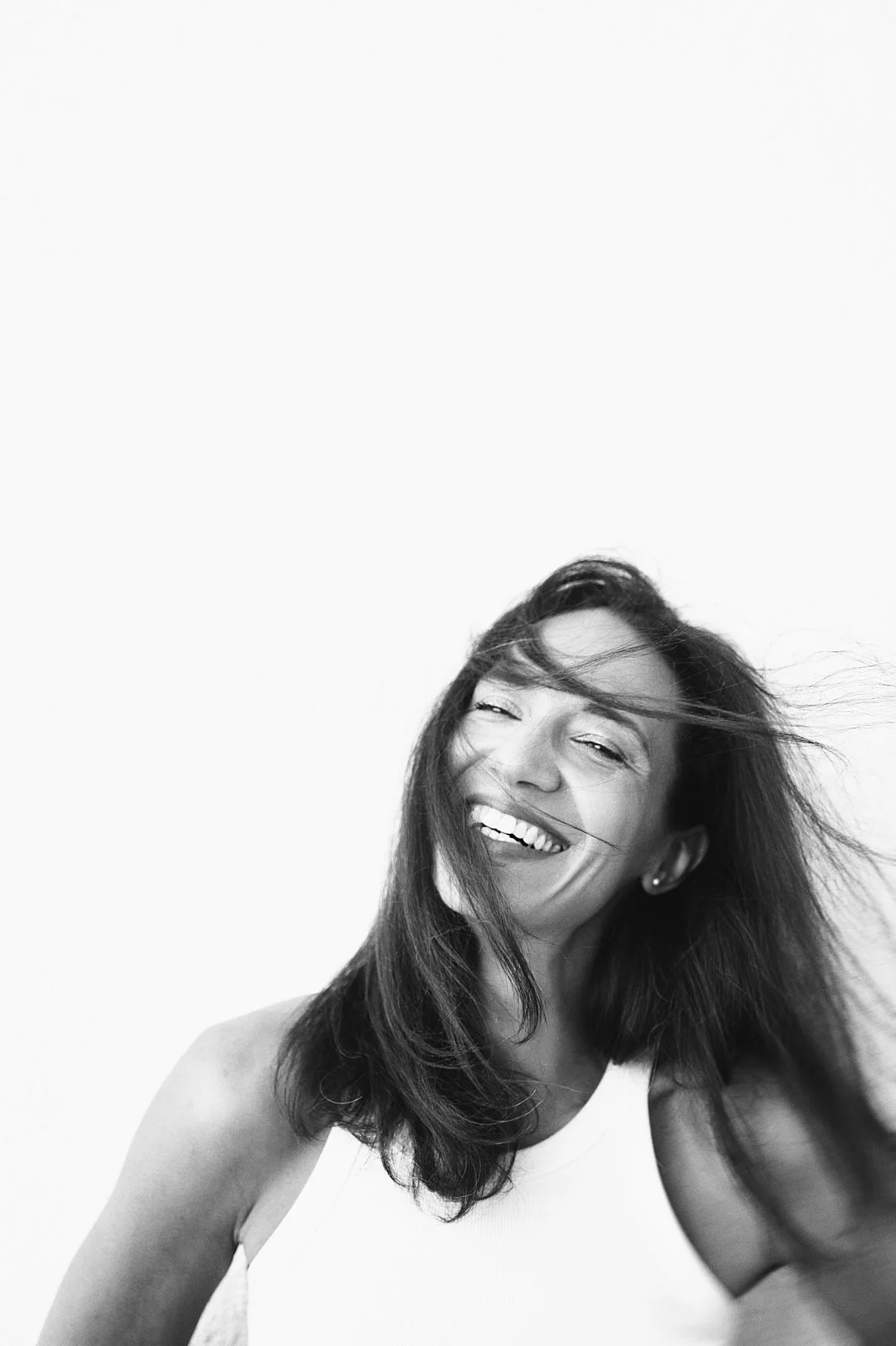 A woman with shoulder-length hair smiling and looking joyful in black and white portrait.