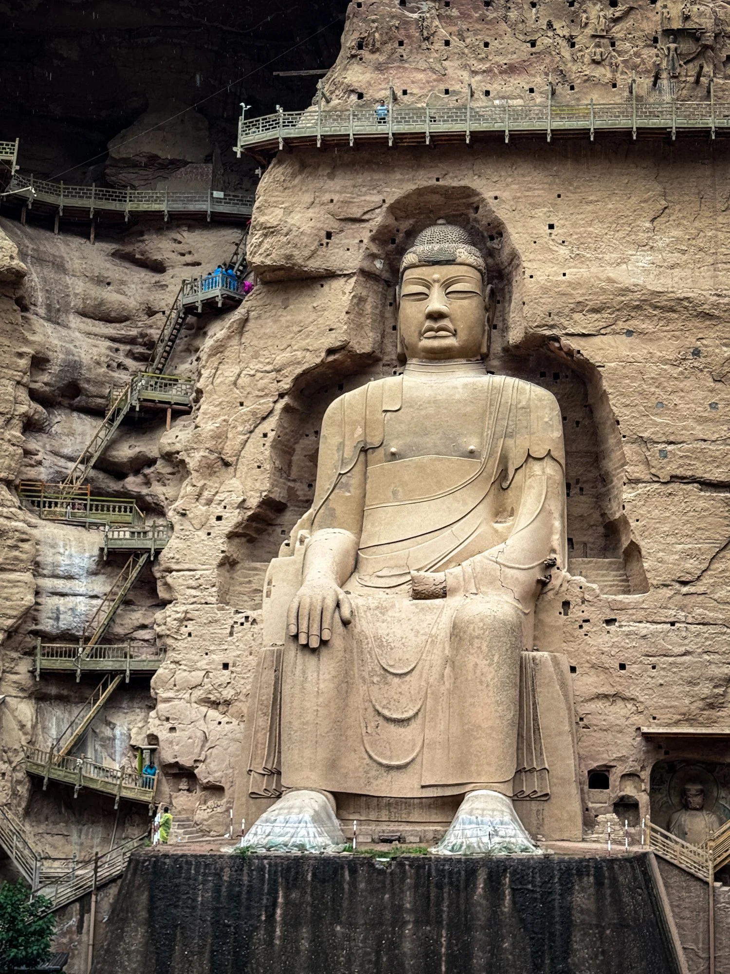 A giant Buddha statue with feet wrapped in plastic