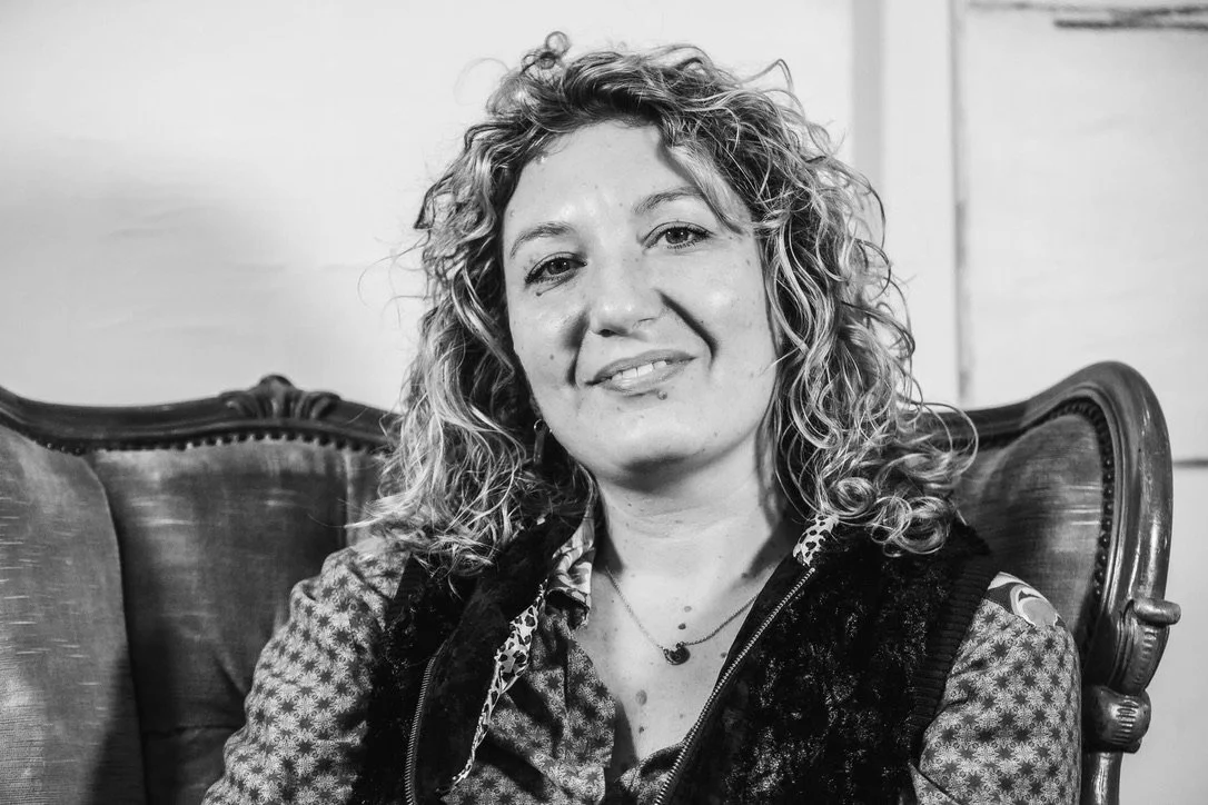 Ritratto in bianco e nero di una donna con capelli riccioli seduta su una sedia antica