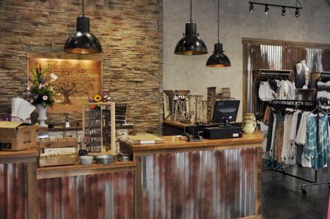 Lizard Thicket Boutique in McDonough, GA - featuring a transaction counter/cash wrap with a countertop built from reclaimed wood and wrapped in corrugated metal, with a cultured stone wall