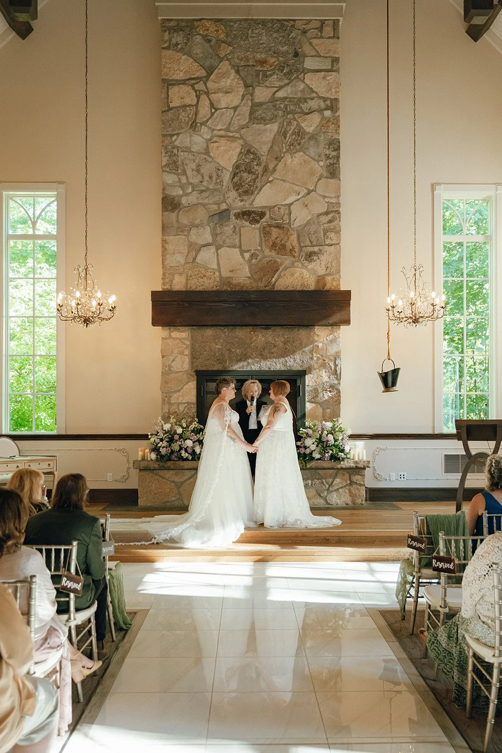 Two brides holding hands at their ceremony at the Ancaster Mill in Ontario