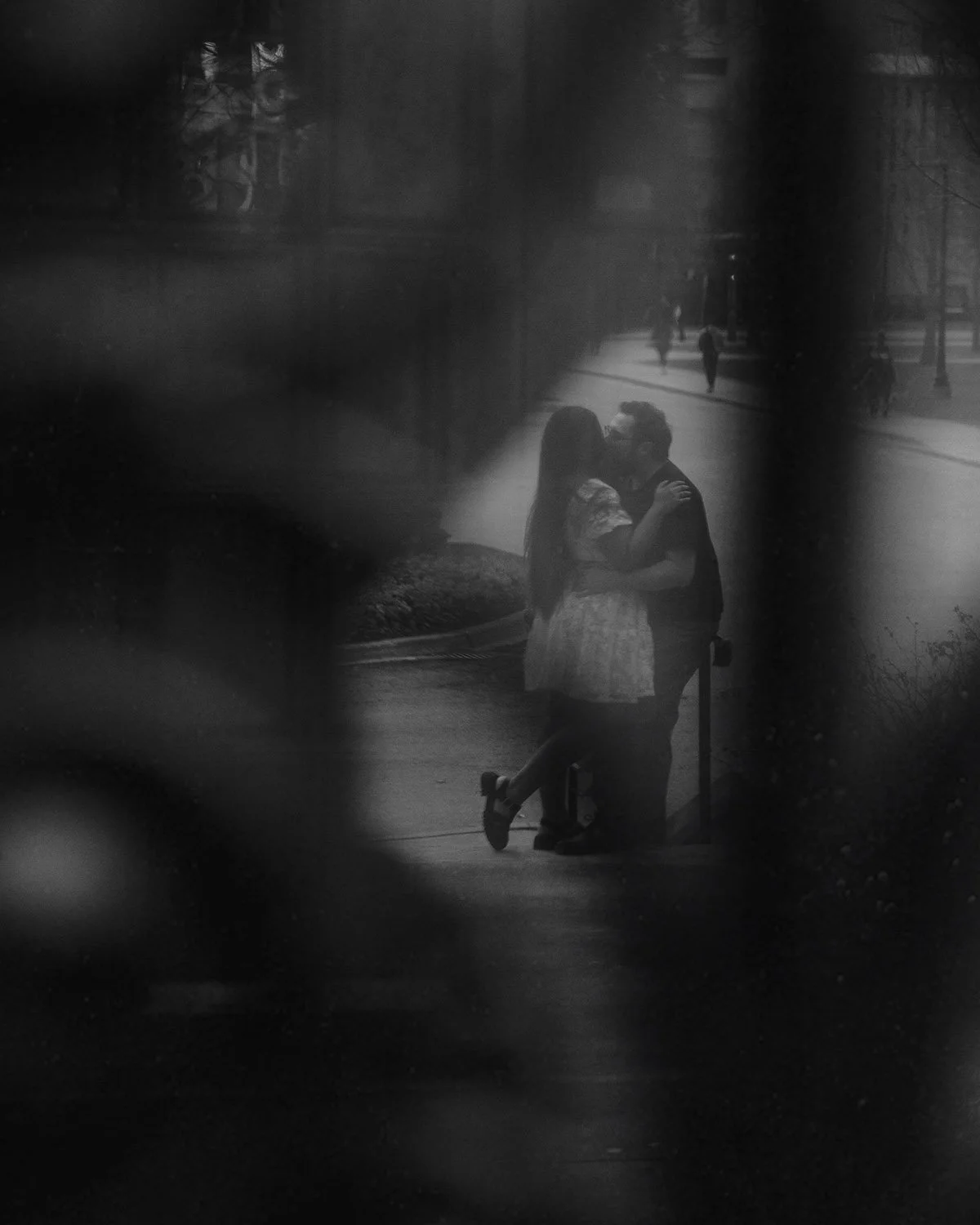 An engaged couple embraces and kisses on campus in Hamilton, Ontario