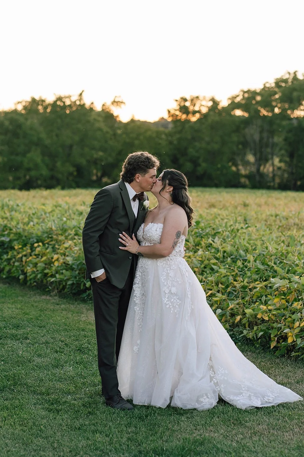 Couple kissing in a field during golden hour in a documentary-style Ontario wedding photo