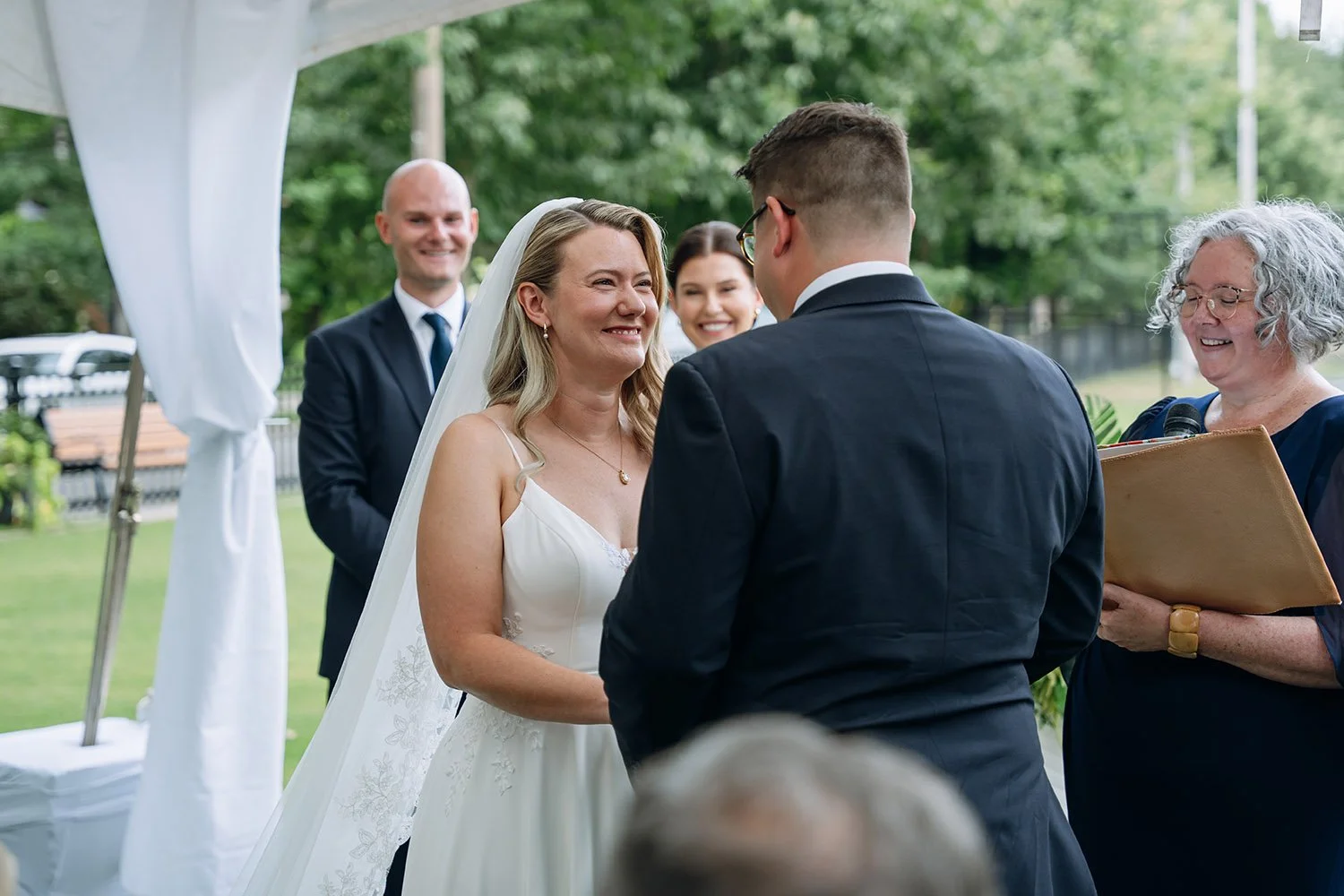 A bride giggles and looks lovingly at her groom at their wedding ceremony in Toronto