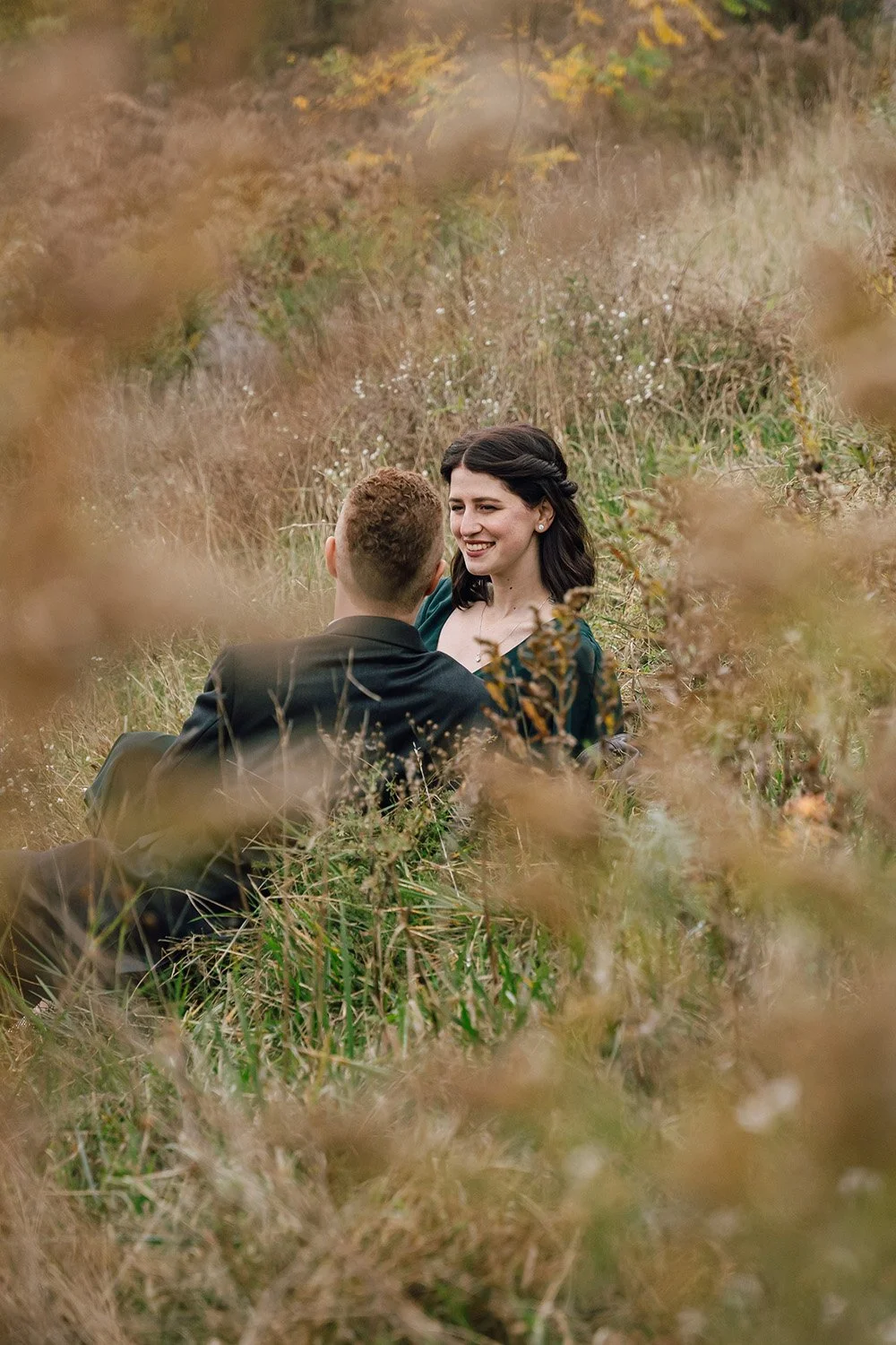 Bride and groom lounging together in a field during their Ontario wedding portraits, captured by a documentary-style wedding photographer.