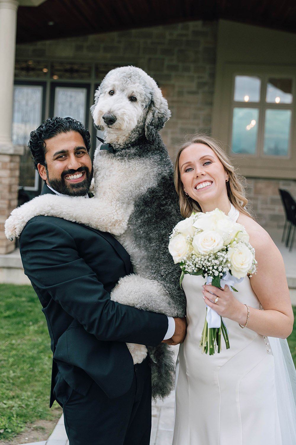 A bride and groom smiling with their dog at an intimate wedding ceremony in Hamilton, Ontario