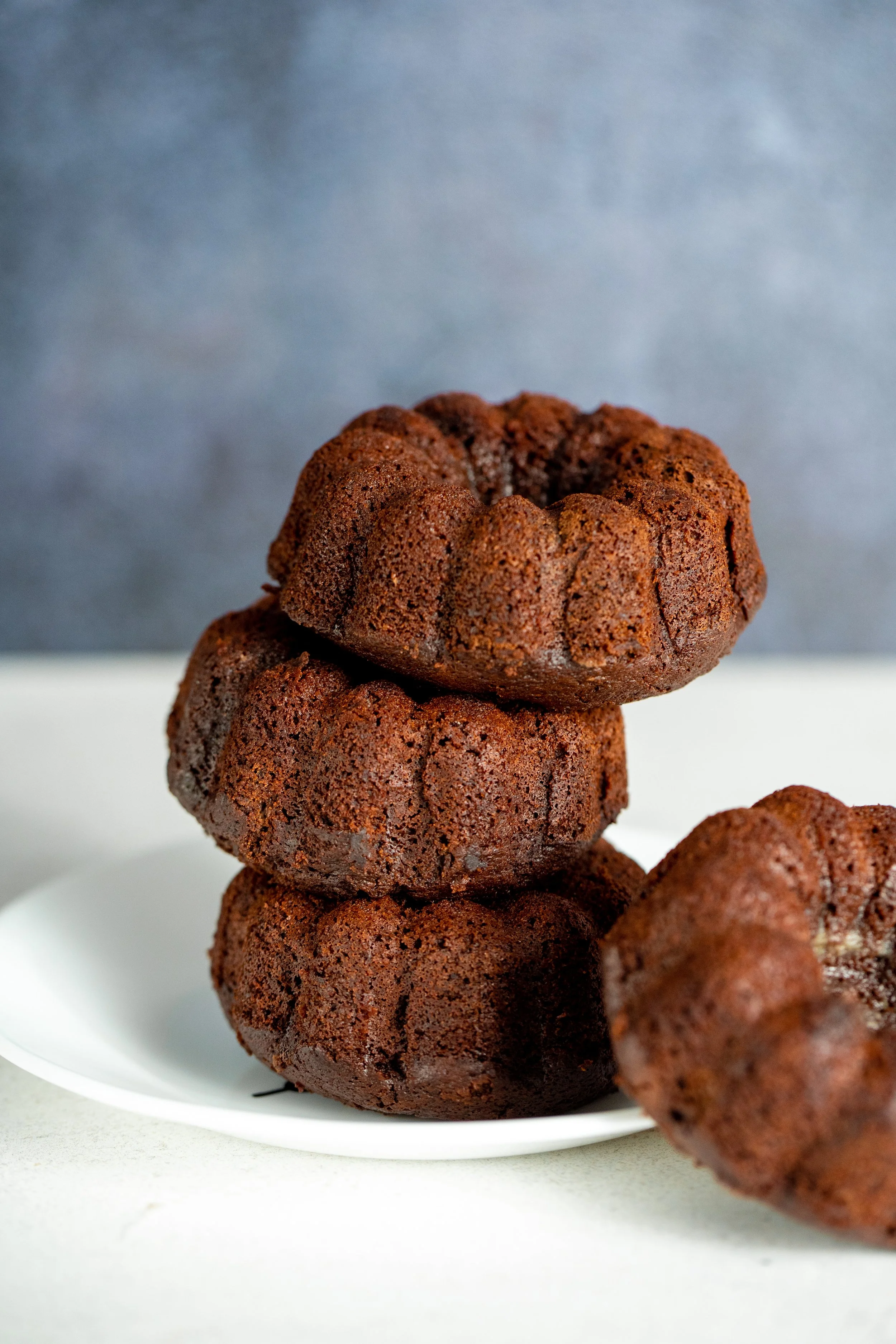 Stacked chocolate crinkle cookies on a white plate with a gray background.