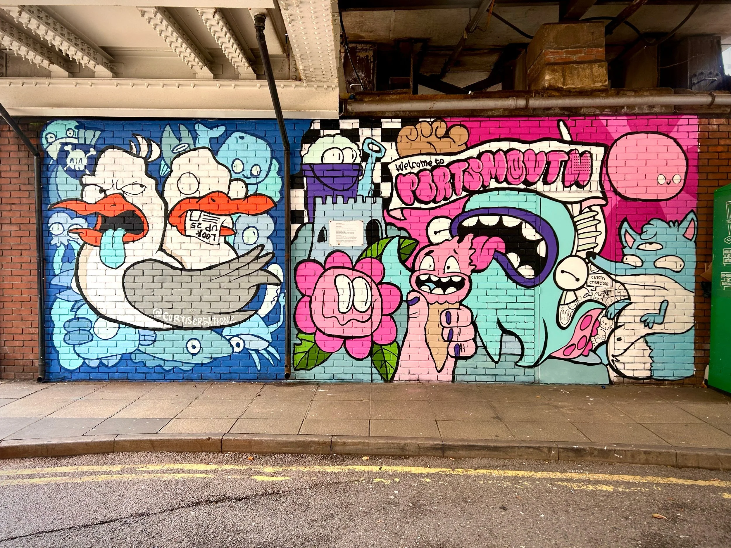 Colorful street art mural on brick wall featuring cartoon-like characters, including a white duck with an orange beak, a pink character, a white ghost, and various other playful figures, with the word "PERFORMOUT" in stylized pink letters.