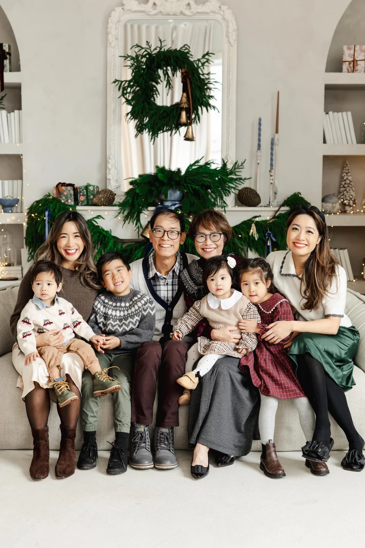 Grandparents, two mothers and four young children on a sofa.