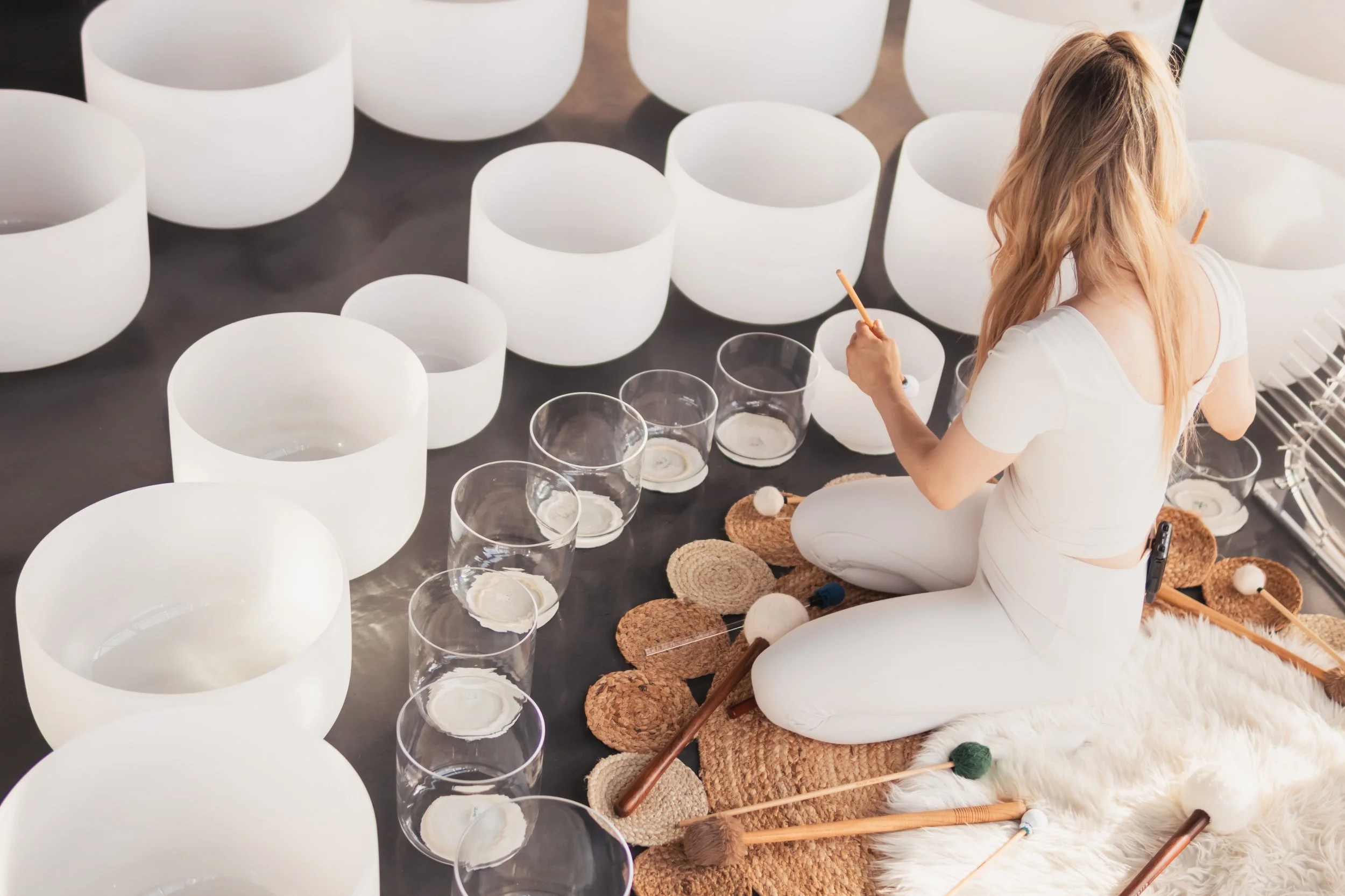 Carine A Hamid assise parmi des bols de cristal lors d’un bain sonore