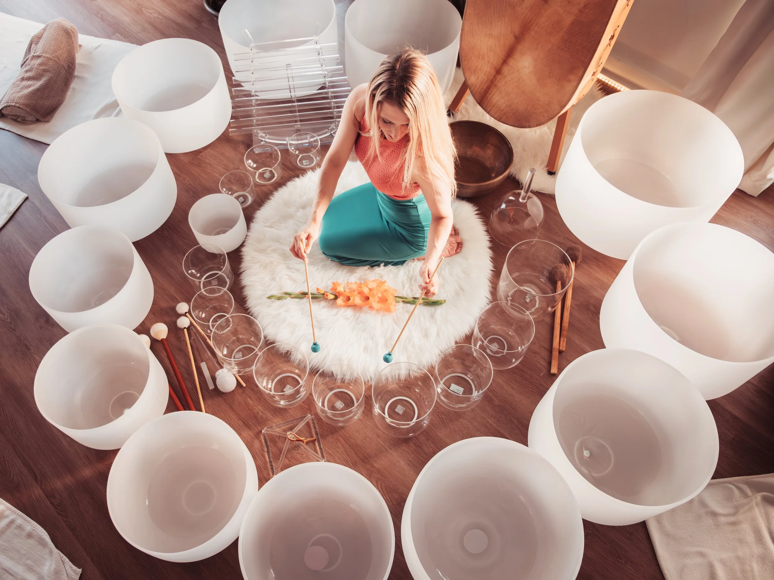 Femme au centre de bols chantants de cristal lors d’un soin sonore