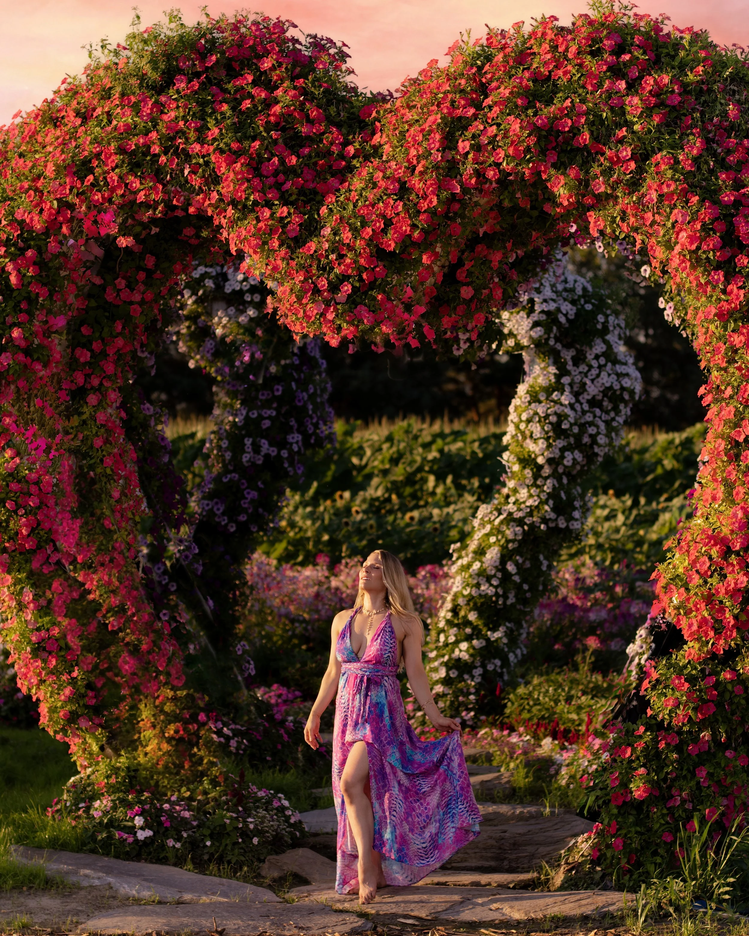 Une femme traverse une arche fleurie en forme de cœur, sous la phrase « La douceur illumine le centre-cœur d’harmonie