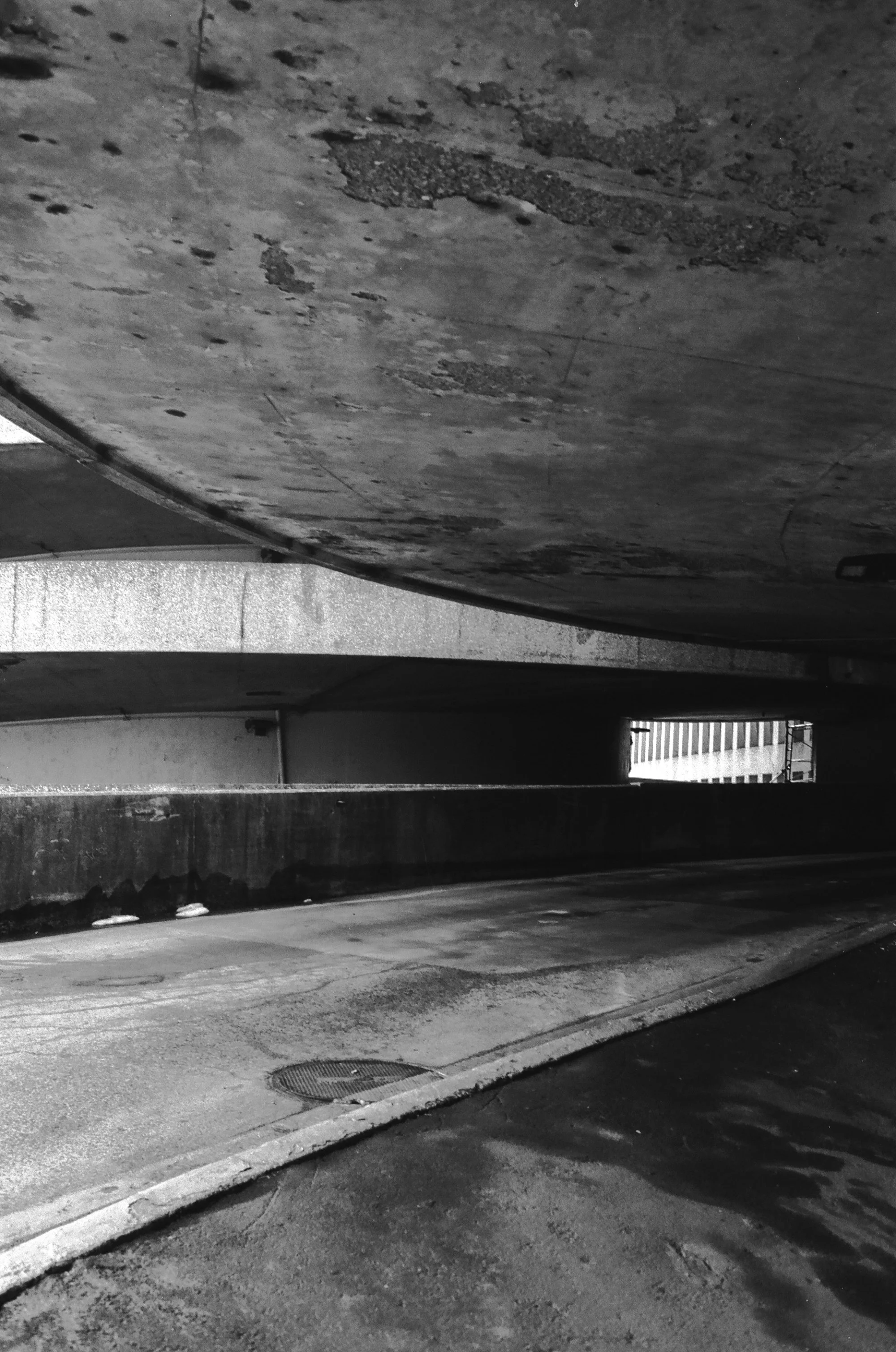   the circular flow of the queens place mall extends unto the parking garage’s entry/exit ramps thanks to their spiral shape  