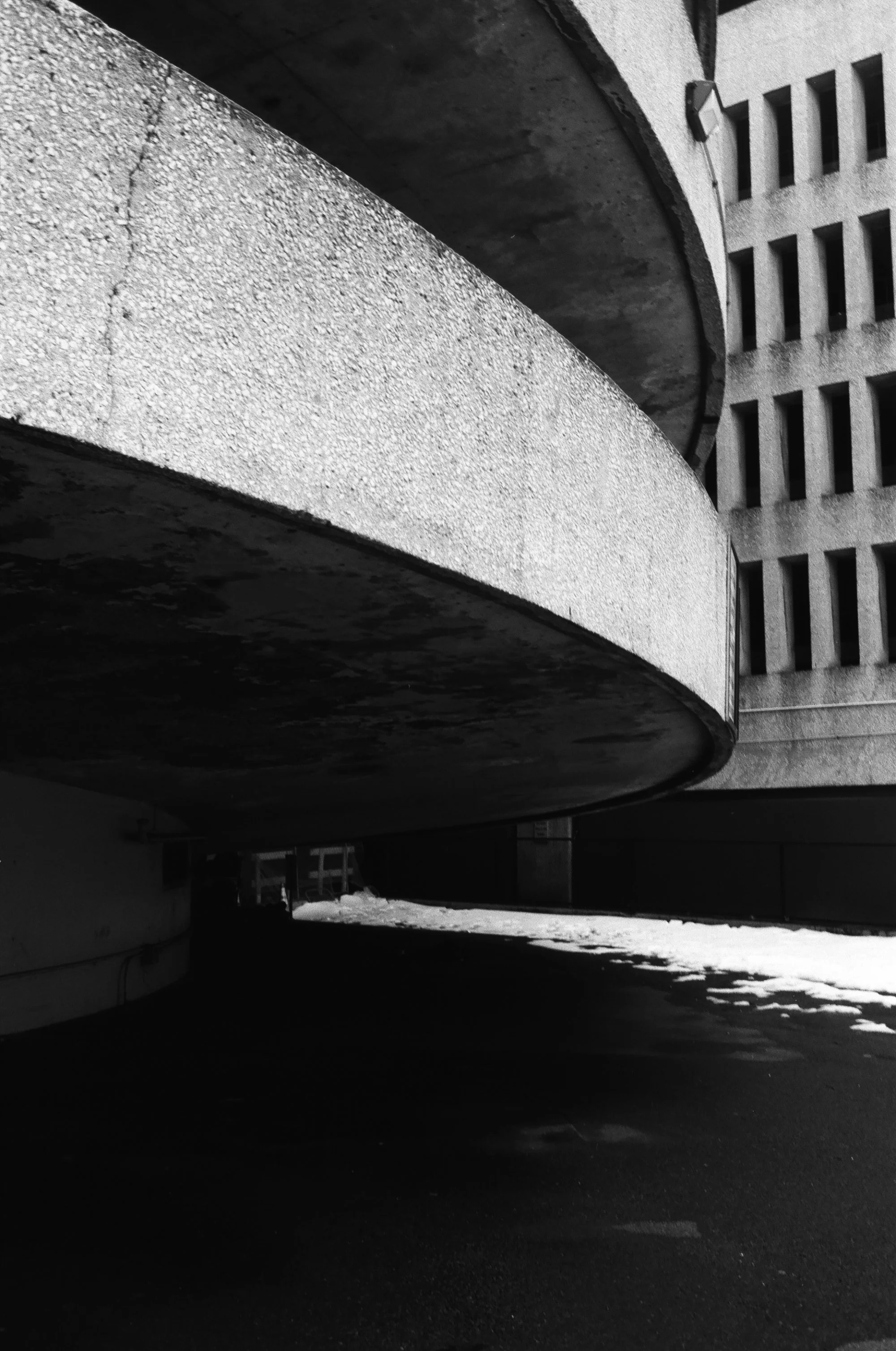   the circular flow of the queens place mall extends unto the parking garage’s entry/exit ramps thanks to their spiral shape  