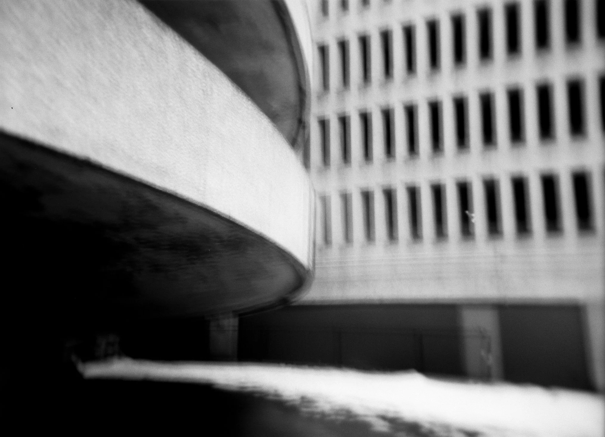 the contrast between the smooth concrete of the queens place mall's entry/exit ramps and the coarse texture of its main façade