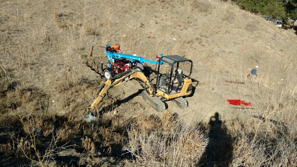 Mini excavator with a robotic arm on rough terrain