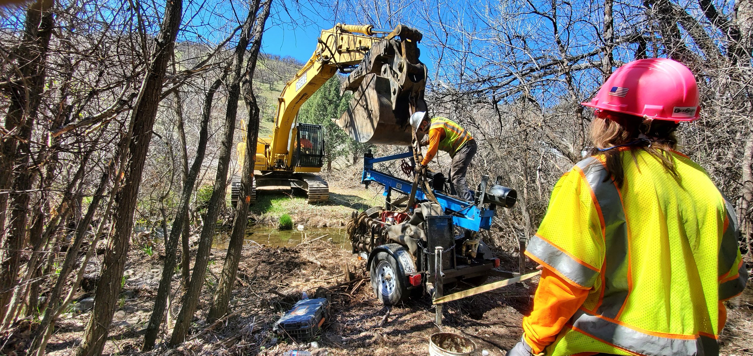 Construction workers operating heavy machinery in a wooded area