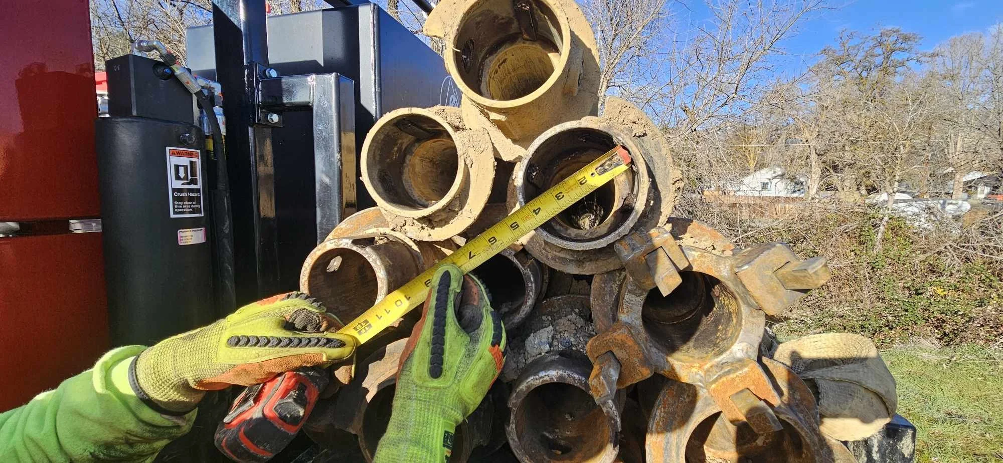 Person measuring rusty metal pipes with tape measure outdoors