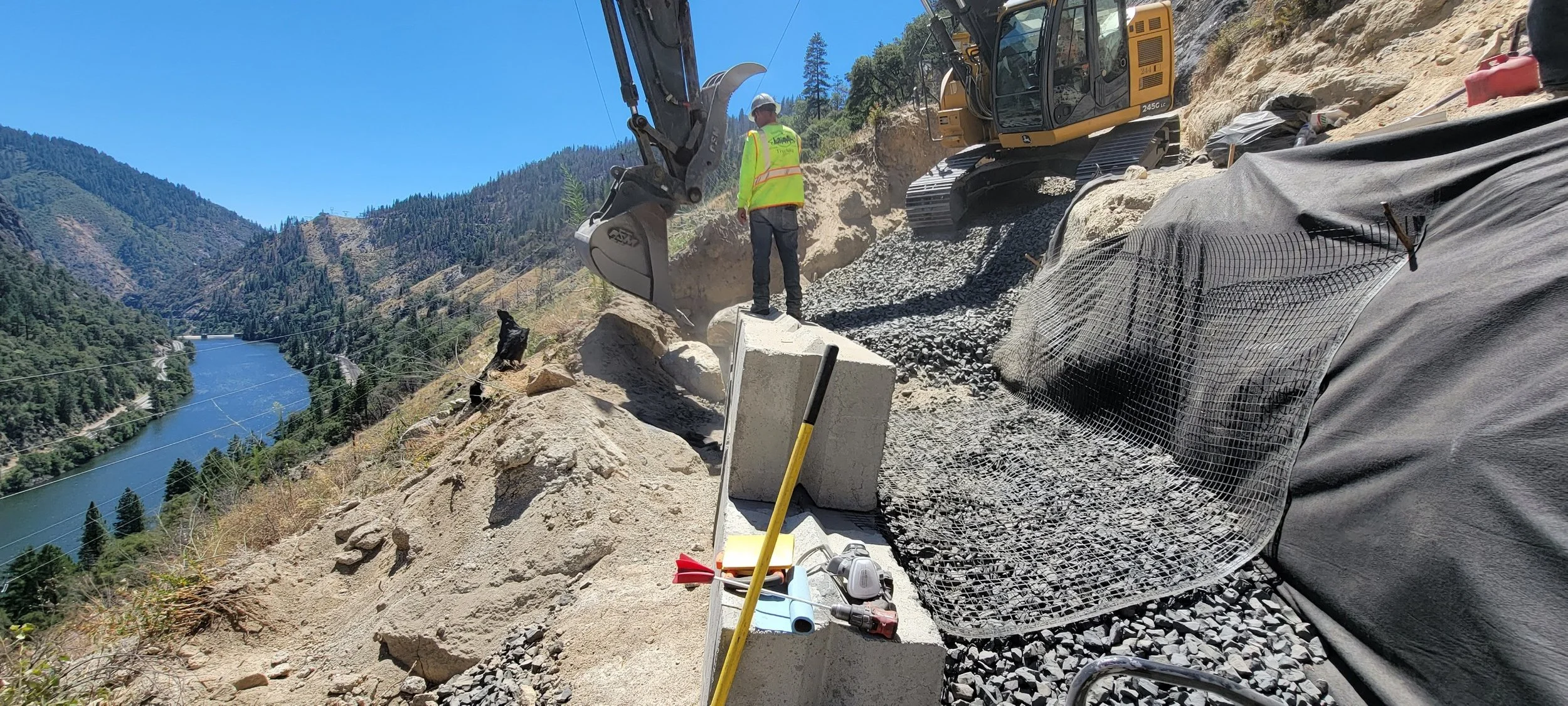 Construction site on mountainside with excavator and worker