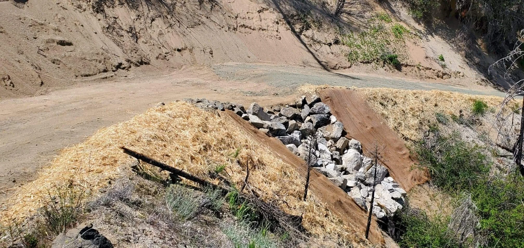 Landslide erosion control with rocks and straw mulch on slope
