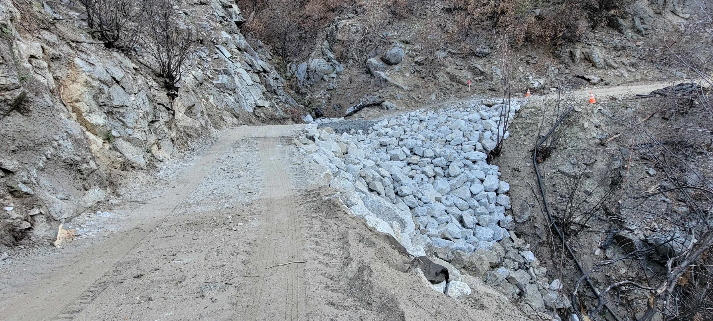 Gravel mountain road with rocky terrain and bare trees