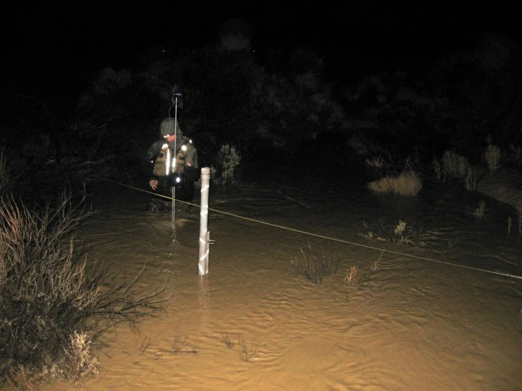 Person in floodwaters at night with measuring equipment