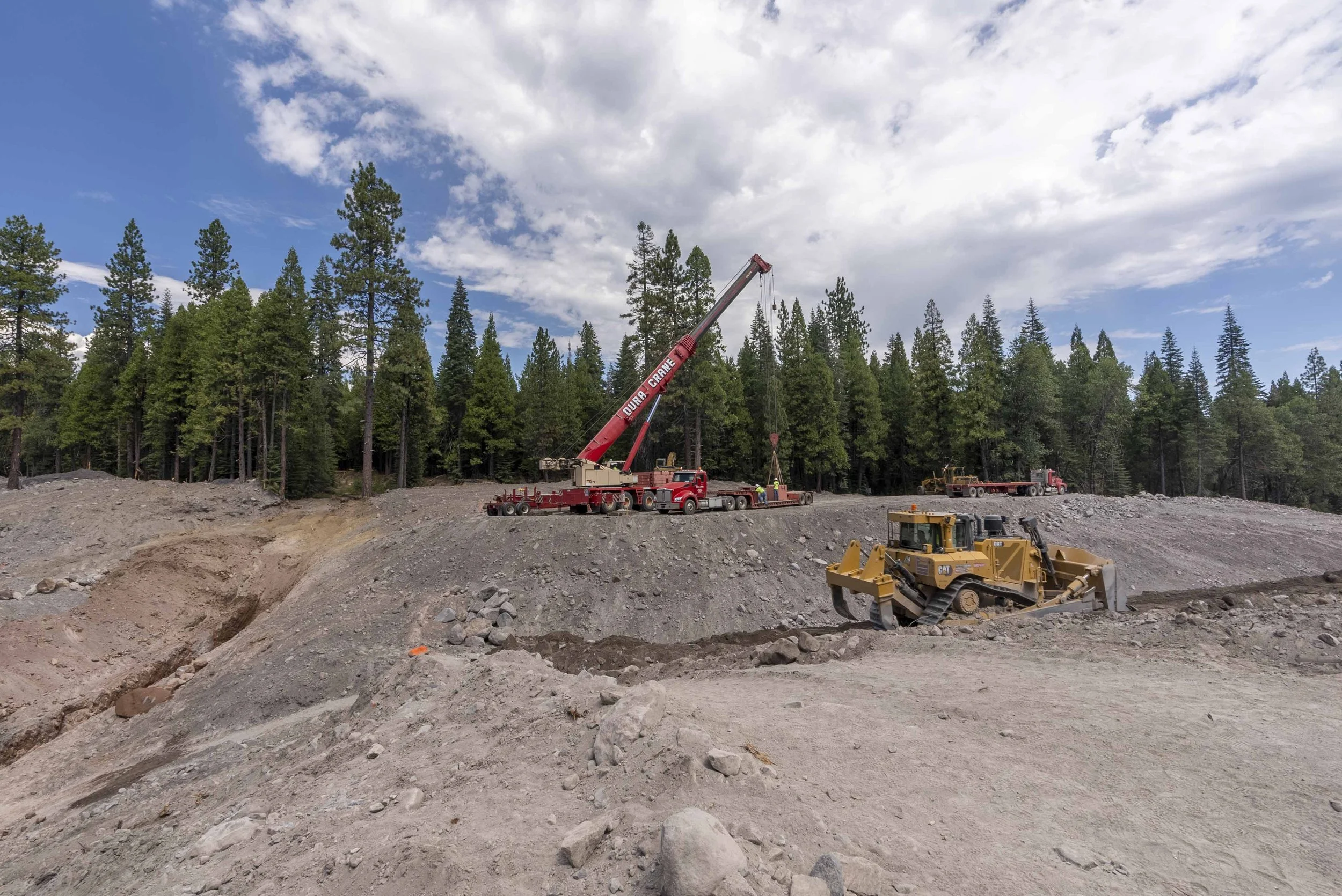 Construction site with trees, crane, and bulldozer