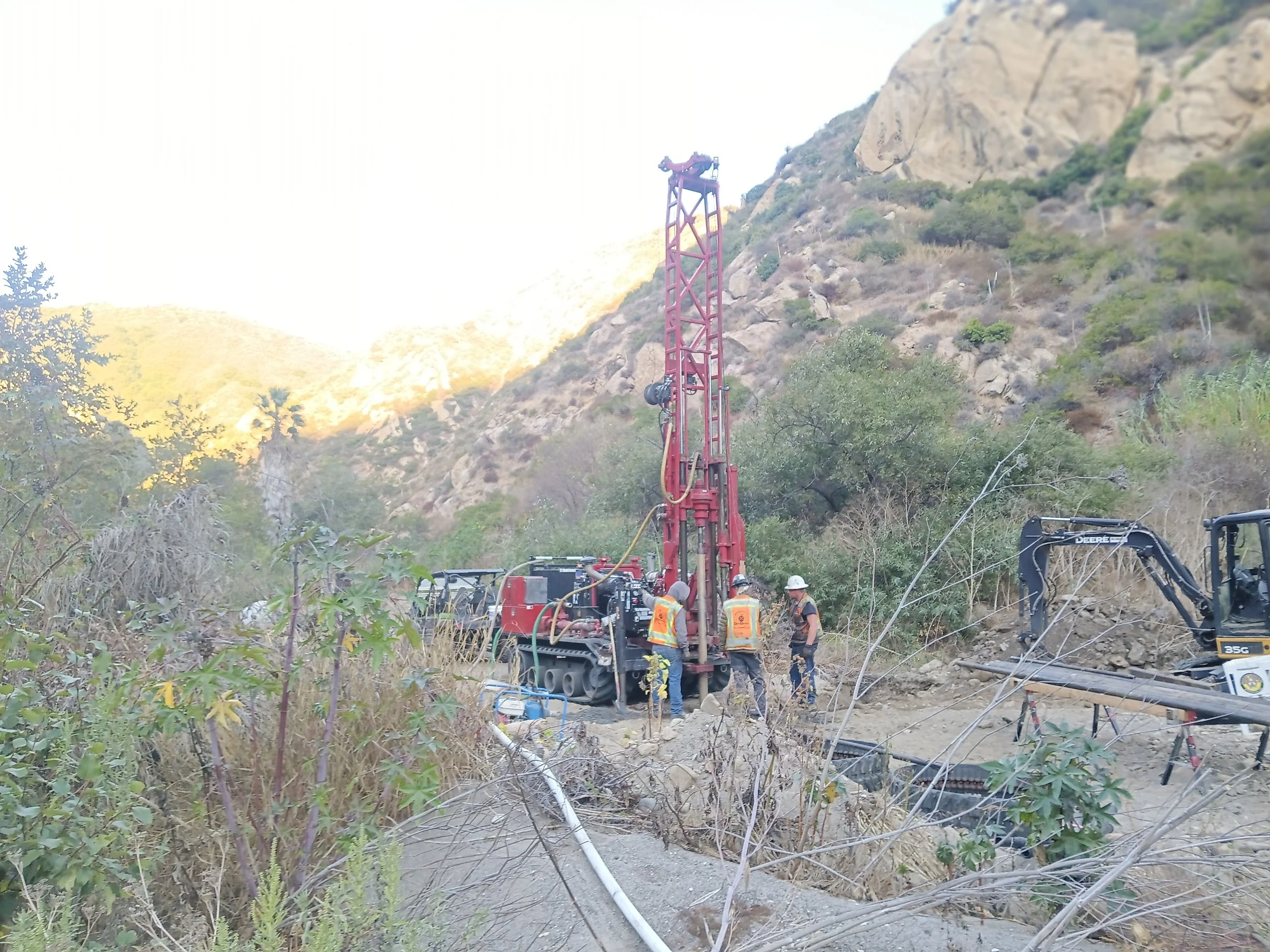 Construction site with drilling machinery and workers in a mountainous area