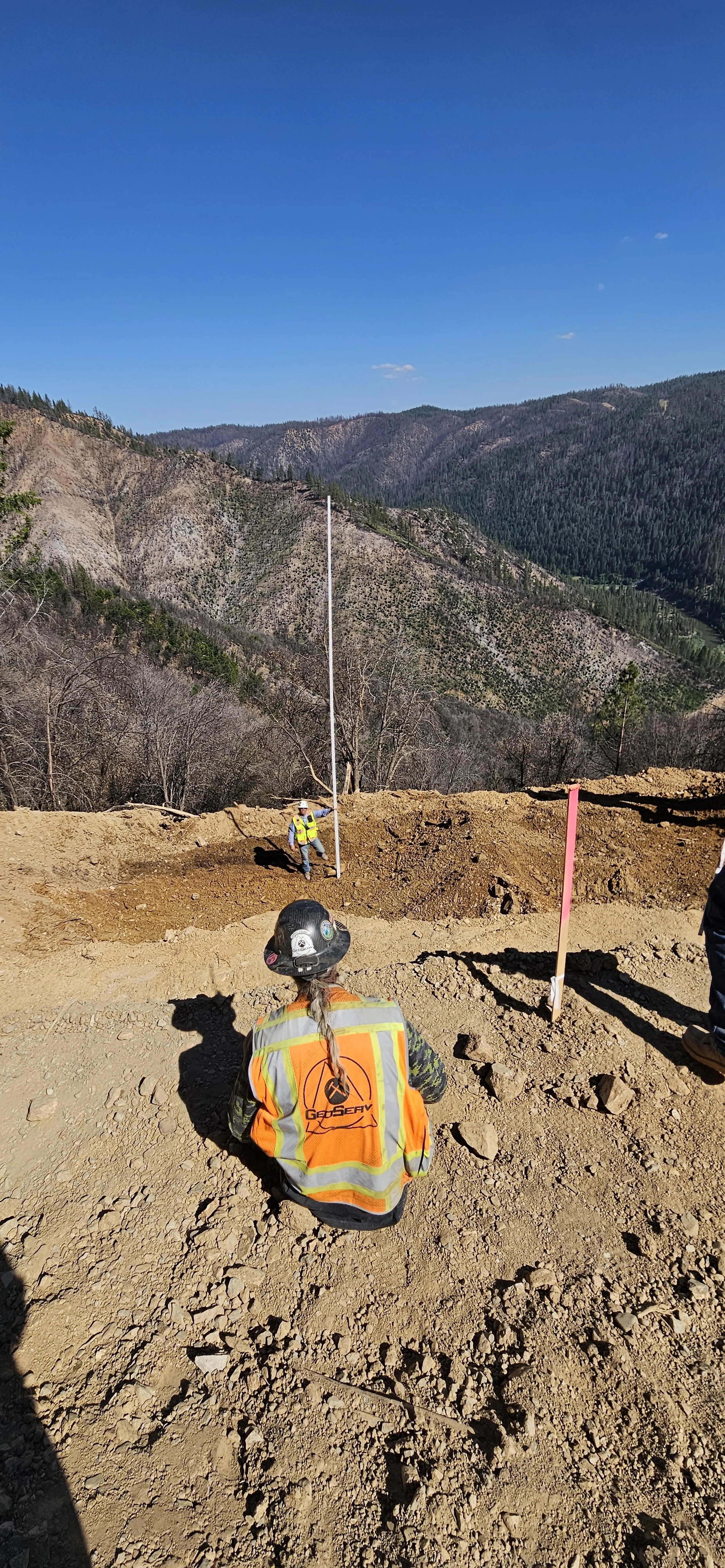 Construction workers on a dirt site with mountains in the background