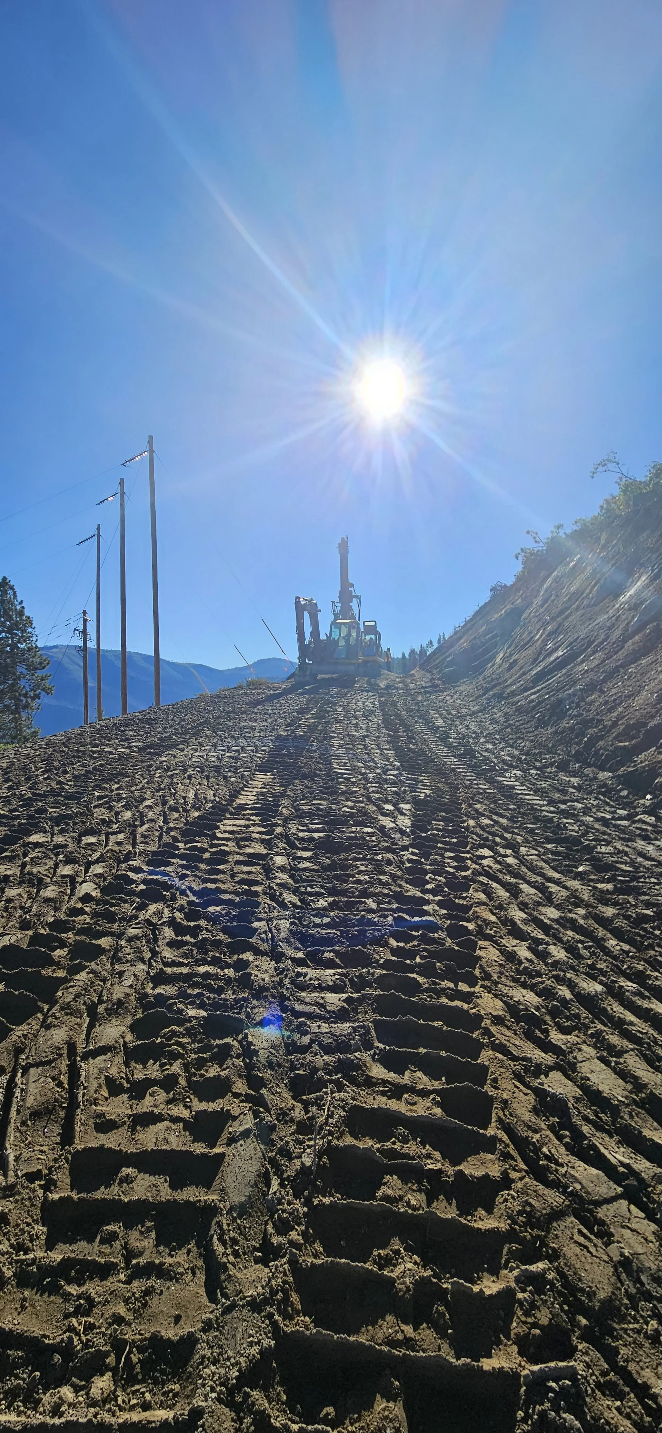 Construction site with heavy machinery on a dirt path under a bright sun