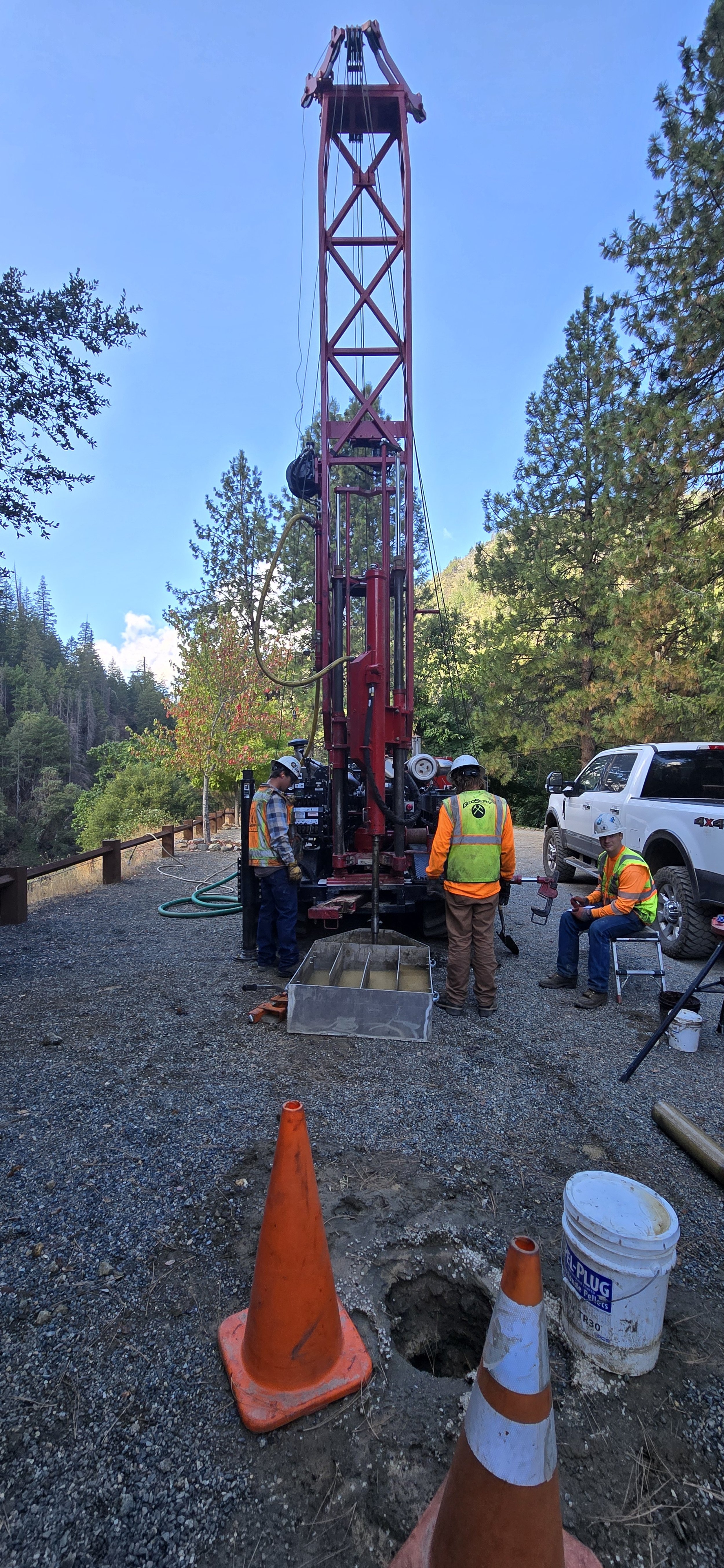 Geotechnical drill rig at construction site with workers in safety gear.