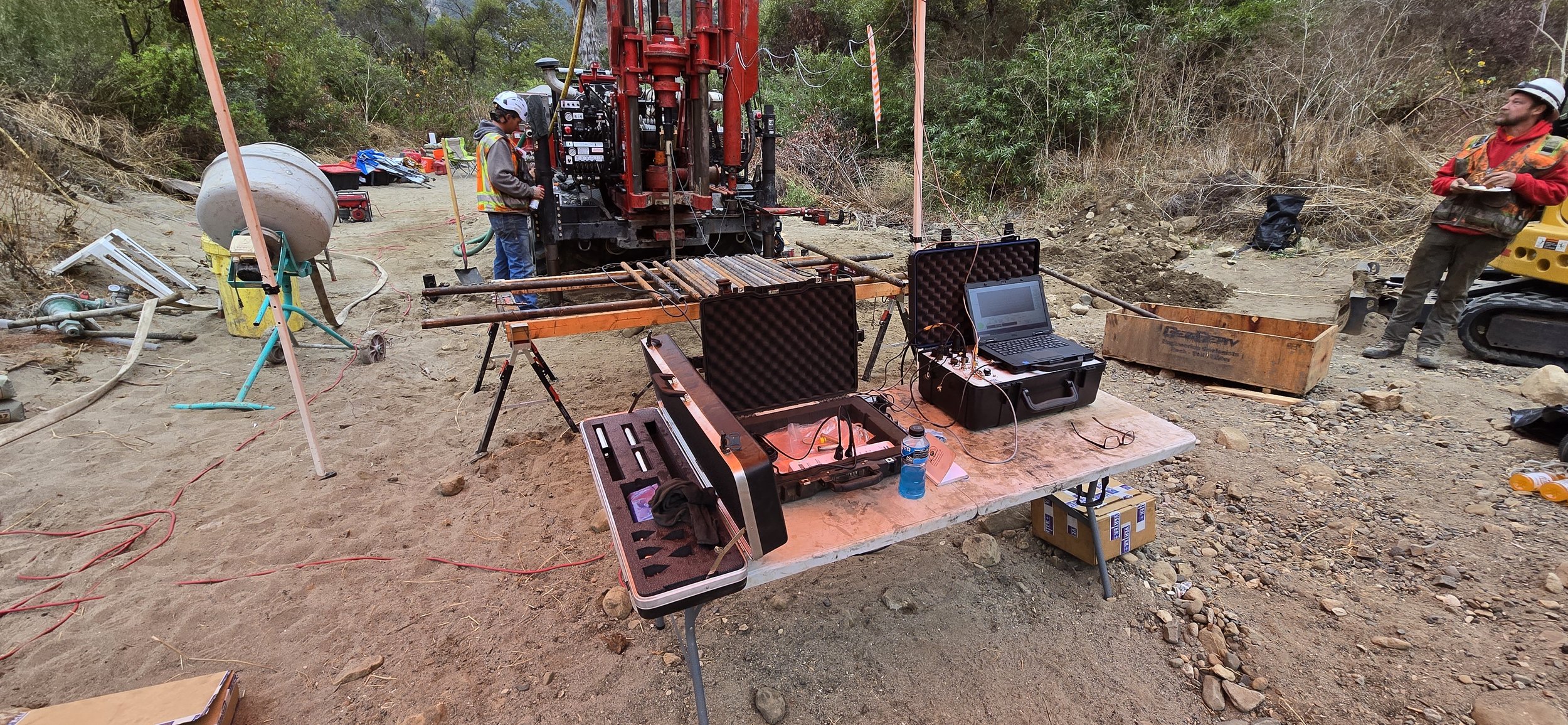 Field laboratory setup with drilling equipment and workers on a construction site.