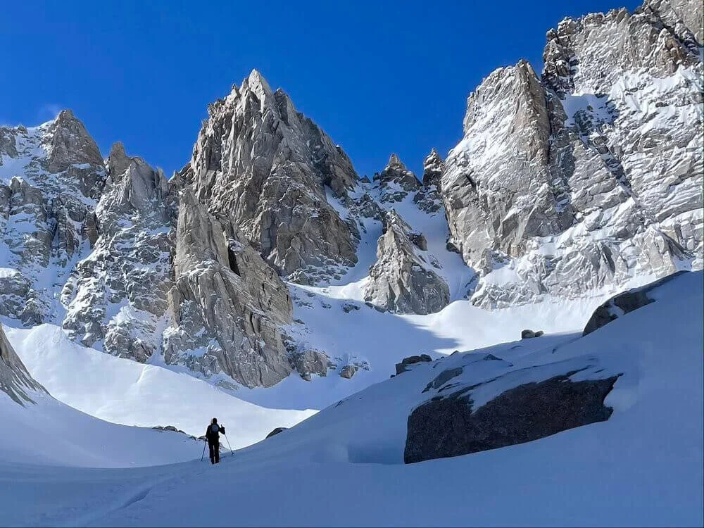 woman cross-country skiing surrounded by cliffs