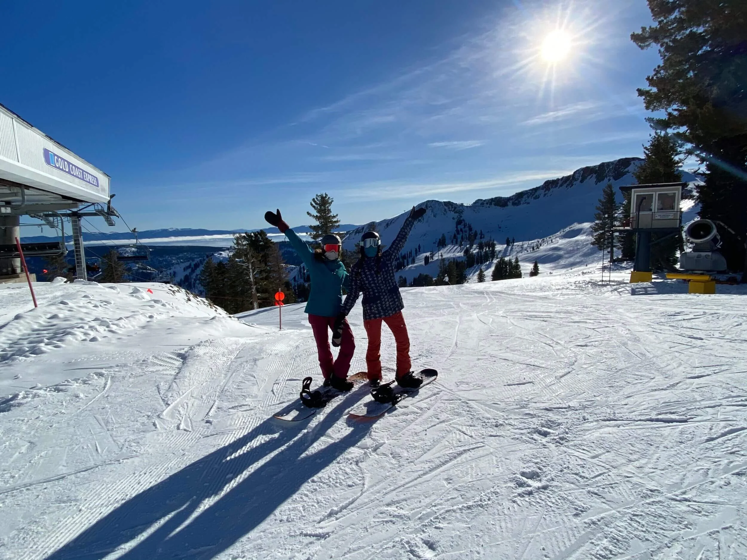 two women snowboarding with arms raised