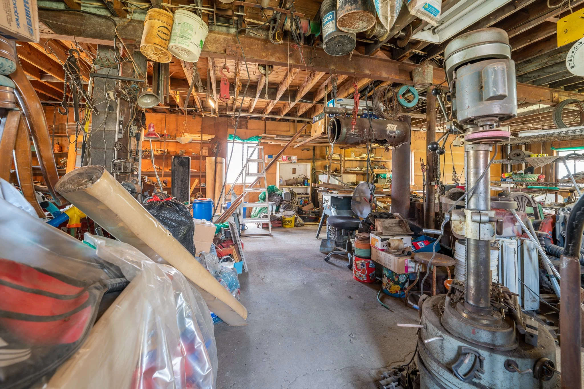 This image shows the interior of a residential workshop that has gotten out of hand. The space is so full that it's hard to imagine what it could be like. 