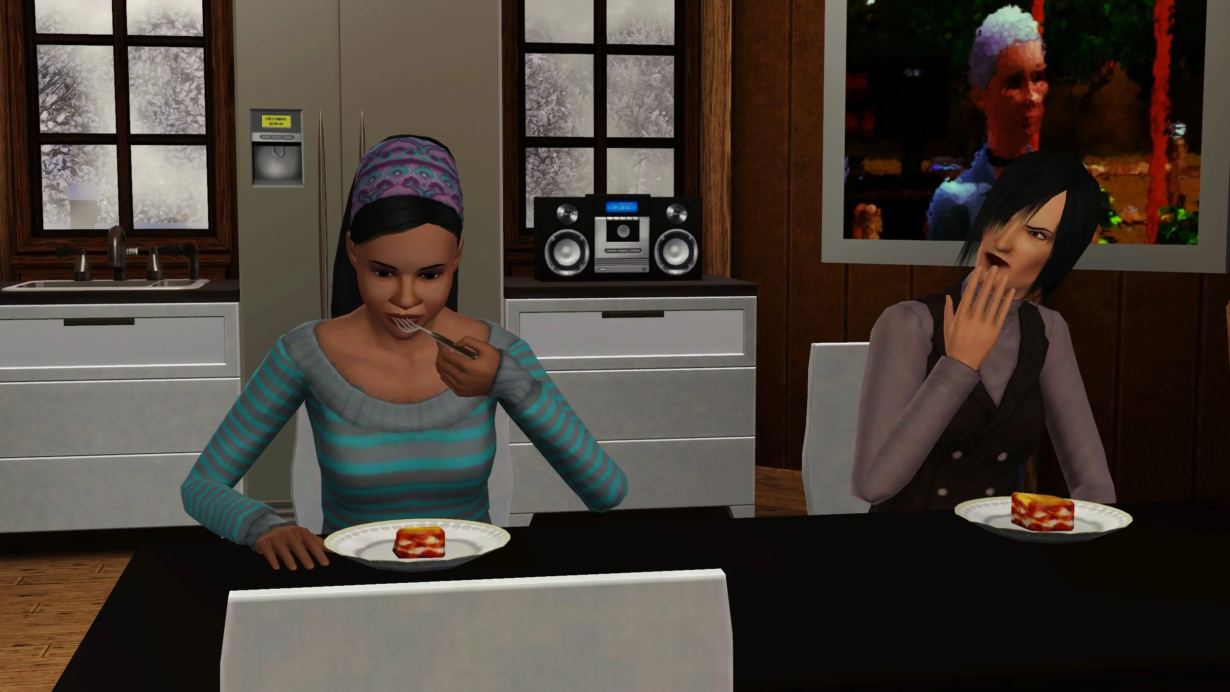 Emery and Colette sit next to each other at a dining table with plates of lasagna. Emery has a forkful in her mouth, Colette is tapping her mouth/chin thoughtfully. Behind them are Emery’s kitchen, winter-frosted windows, and a large painting.