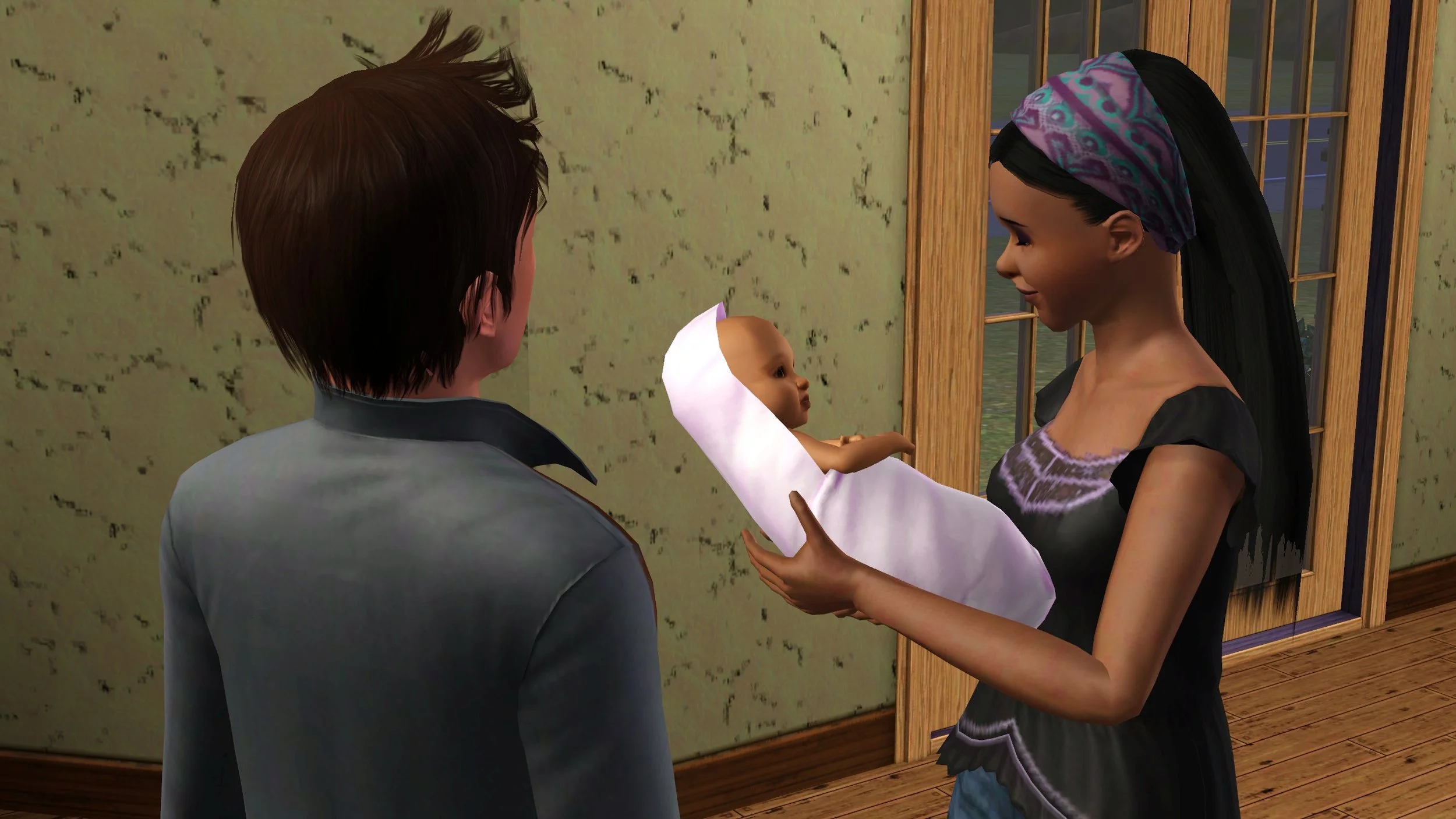 Emery has a relaxed, affectionate expression as she looks down towards baby Mara held in her arms; Matthew stands nearby.