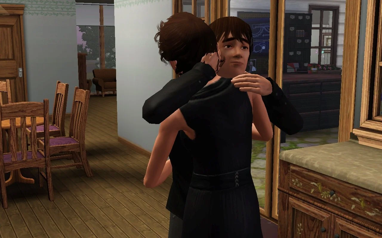 Chase holds Aria in a hug, one hand on her head and the other on her shoulder, while Aria's arms are around his torso. Chase has a sympathetic expression. They're in Aria's parents' kitchen with the dining area visible behind them.