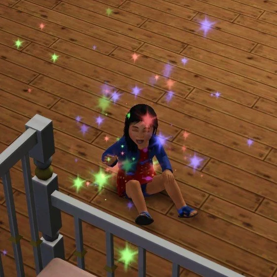Toddler Sim Mara laughs, sitting on the wood floor next to her crib, surrounded in multi-coloured sparkles (from aging up into a toddler). She’s wearing a red dress with an outer space print, blue cardigan, shorts and velcro sandals.