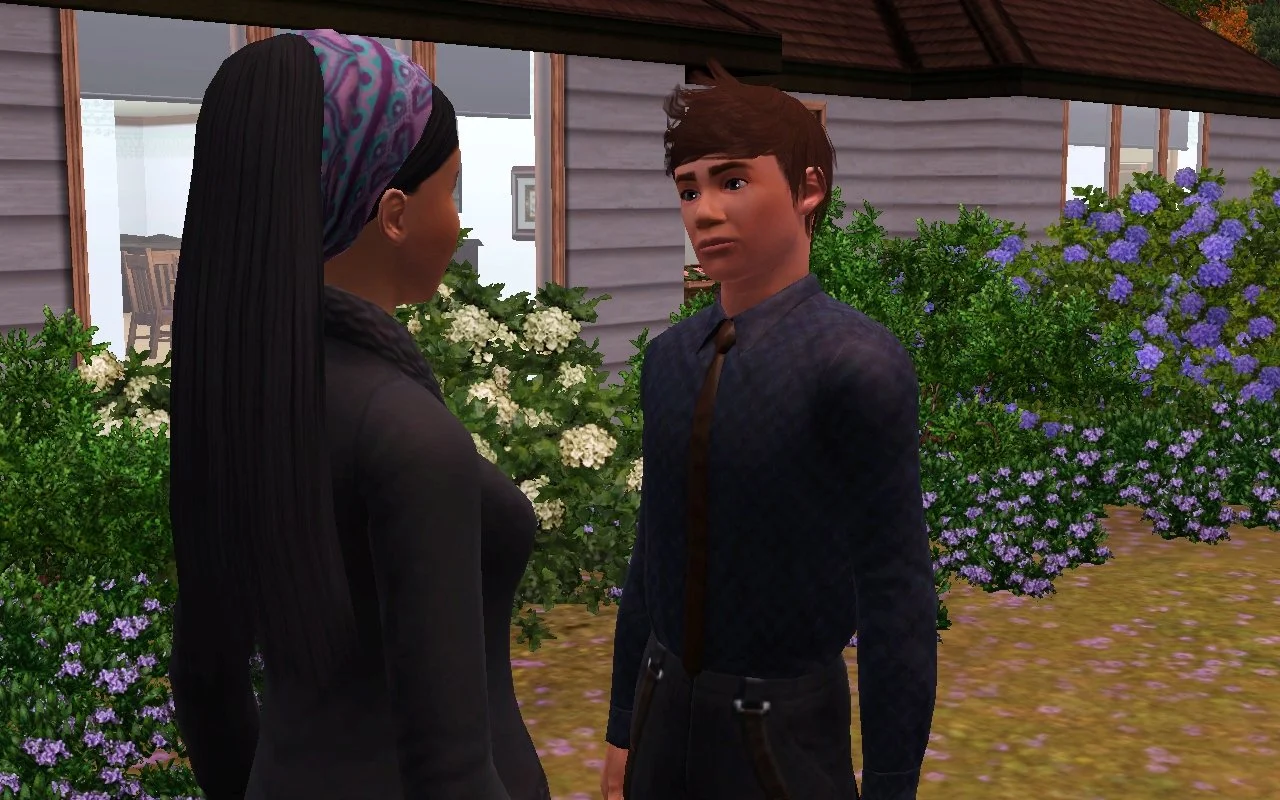 Matthew looks at Emery with a neutral expression in front of their parents' home. Both are dressed in dark formal attire. The house is surrounded in hydrangeas, heather, and evergreen boxwood bushes.