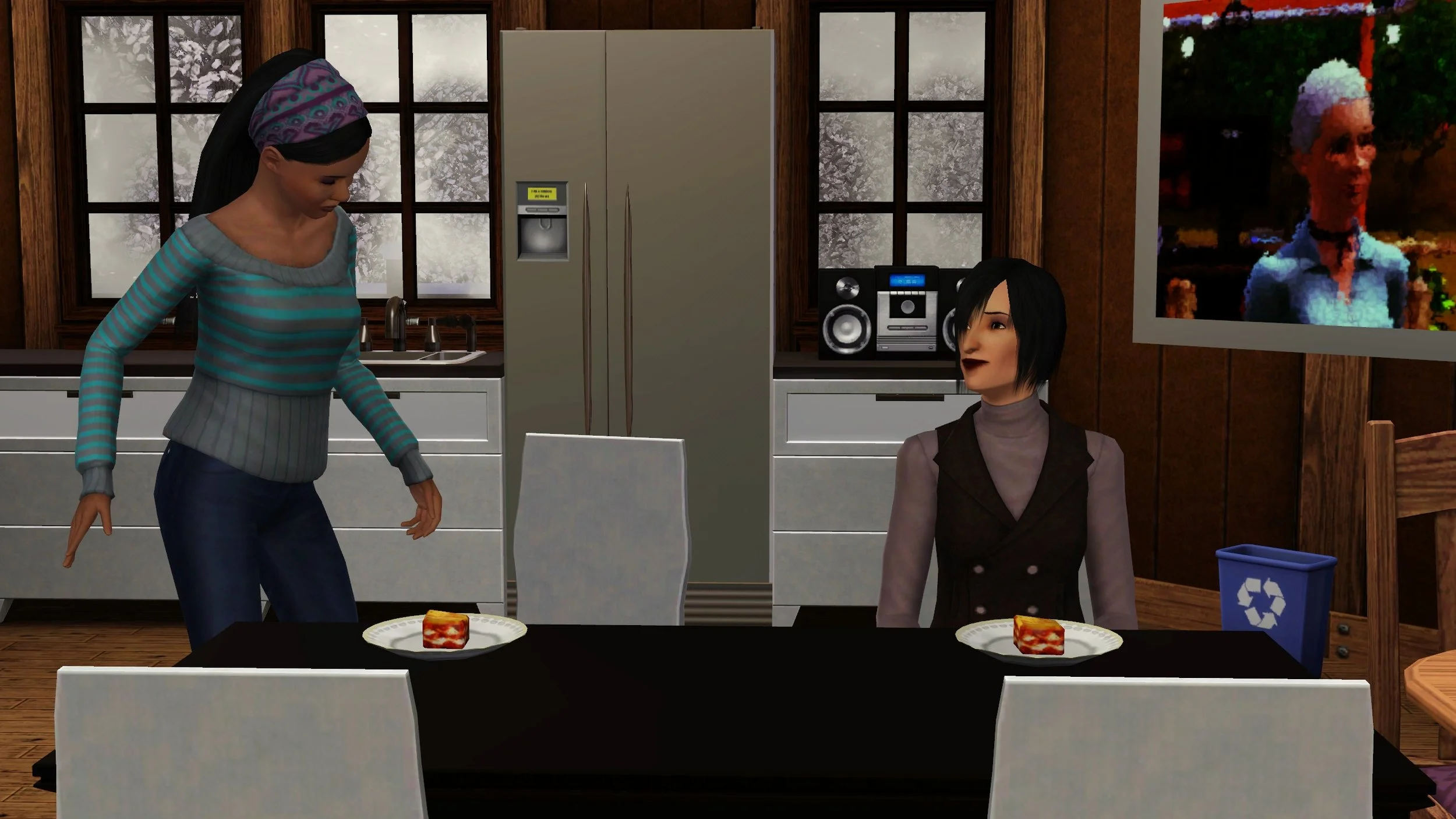 Emery stands next to a dining chair, about to sit in front of a plate of lasagna. Colette sits in the next chair with her own plate, smiling up at Emery. Emery’s kitchen, winter frosted windows, and a large painting of Emery’s mother are behind them.