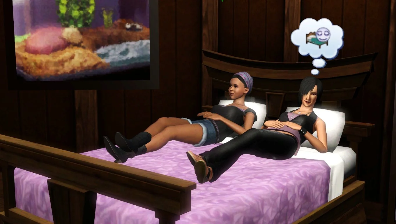 Emery and Colette lay on top of the bed covers, hands relaxed on their stomachs; Colette thinks of the sleepy icon. Emery wears a black blouse, jean shorts, and cowboy boots; Colette wears a lilac tank top, black vest, black jeans and wedge heels.