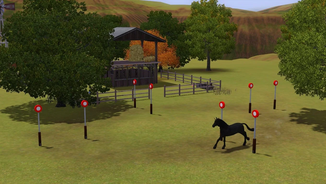 Aasifa the black unicorn runs between pairs of horse racing posts arranged in a loop next to the horse paddock at Button Ranch.